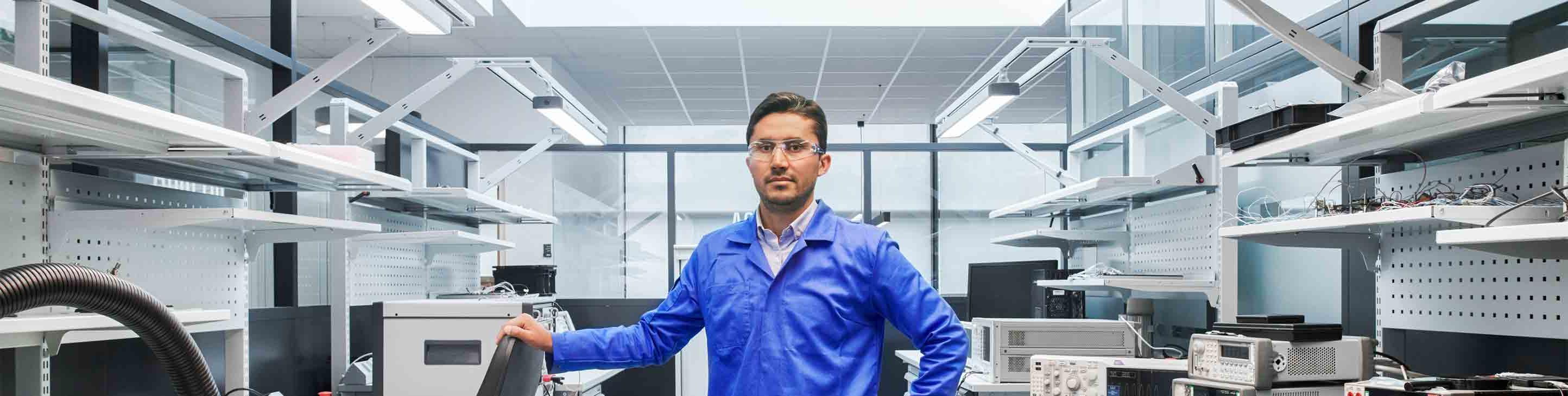穿着蓝色实验服，戴着安全眼镜的人在实验室里摆姿势
